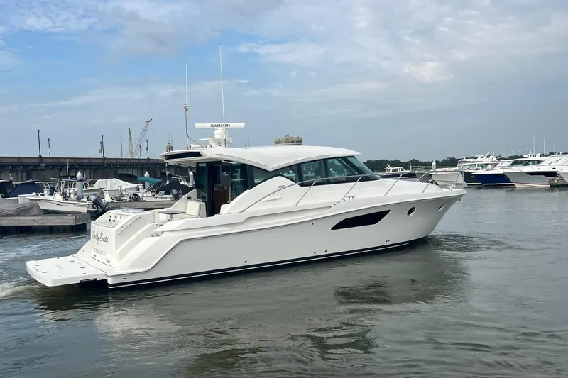 Salty Suite Yacht Photos Pics 2023 Tiara Yachts C44 Coupe cruising in a marina under a cloudy sky.