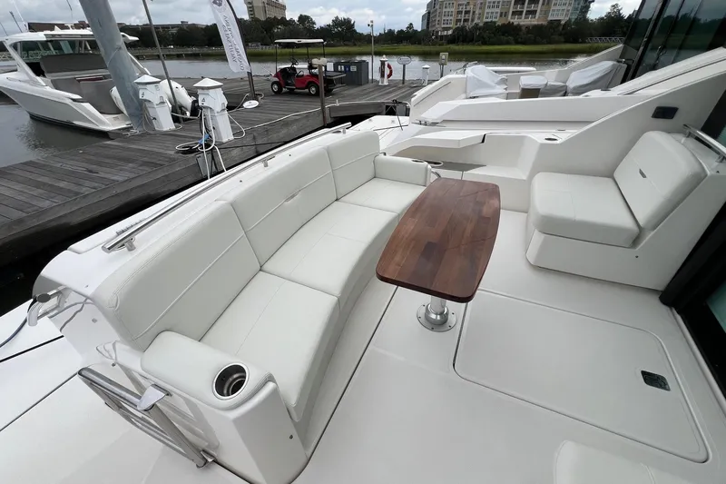 Salty Suite Yacht Photos Pics 2023 Tiara Yachts C44 Coupe, elegant deck seating with wooden table, docked at marina.
