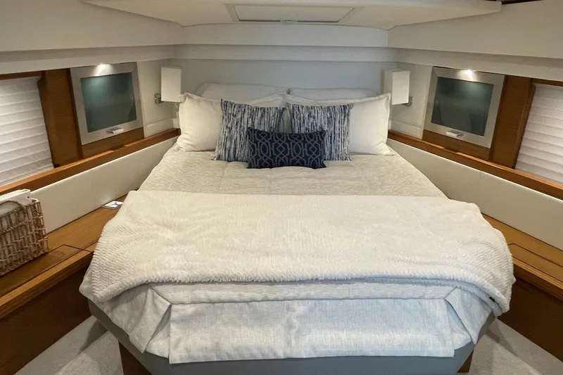 Salty Suite Yacht Photos Pics Luxurious bedroom interior of 2023 Tiara Yachts C44 Coupe with cozy bedding and ambient lighting.