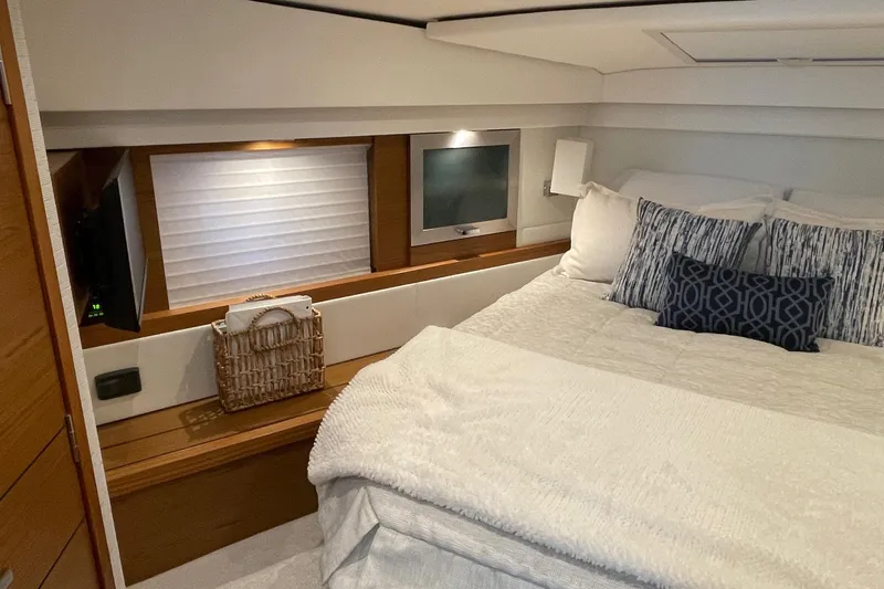 Salty Suite Yacht Photos Pics Luxurious bedroom interior of 2023 Tiara Yachts C44 Coupe with elegant bedding and decor.