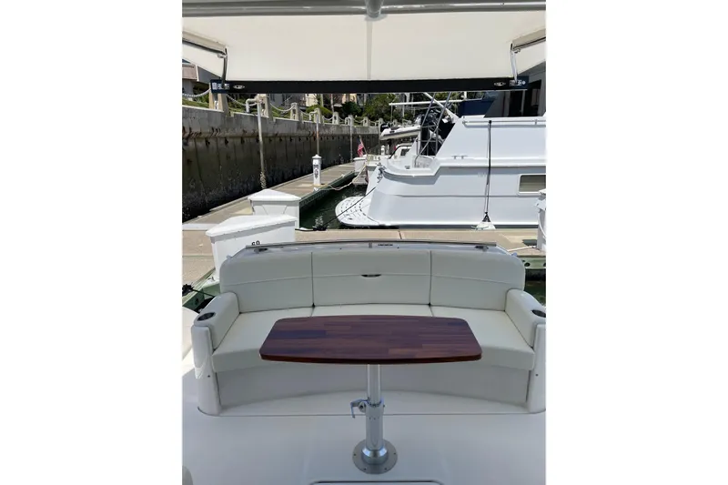 Salty Suite Yacht Photos Pics 2023 Tiara Yachts C44 Coupe with elegant seating and wooden table in marina setting.