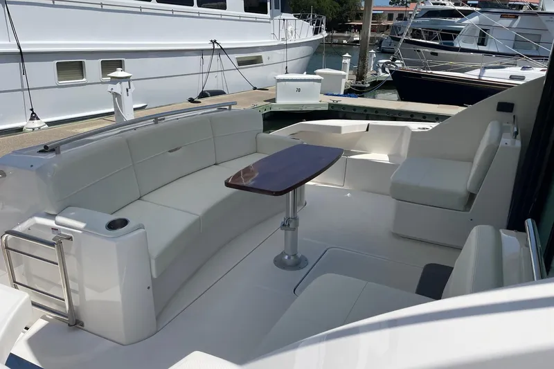 Salty Suite Yacht Photos Pics 2023 Tiara Yachts C44 Coupe cockpit with white seating and wooden table at marina.