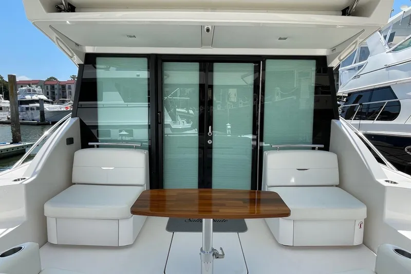 Salty Suite Yacht Photos Pics 2023 Tiara Yachts C44 Coupe cockpit with seating and wooden table, docked at marina.