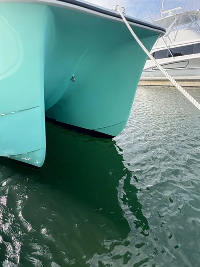 Hull 106 Yacht Photos Pics 2025 Hammer Yachts HammerCat 30 catamaran docked in marina, turquoise hull reflected in water.