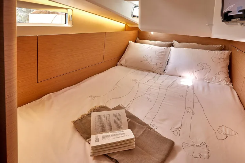  Yacht Photos Pics Cozy cabin interior of 2024 Jeanneau Sun Odyssey 410 with elegant bedding and ambient lighting.
