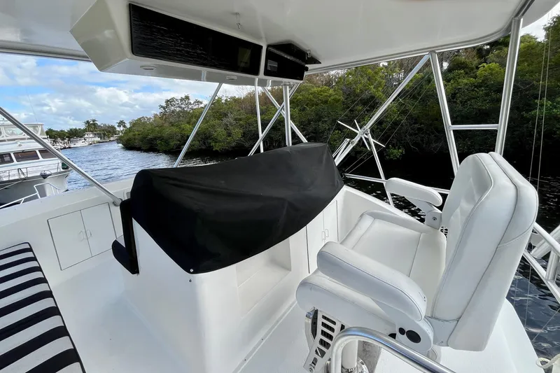 Next Yacht Photos Pics 1999 Post 42 Convertible yacht interior with white seating and covered console, docked near lush greenery.