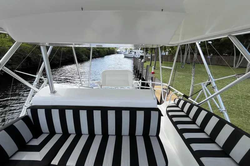 Next Yacht Photos Pics 1999 Post 42 Convertible yacht interior with striped seating, docked by a lush riverside.