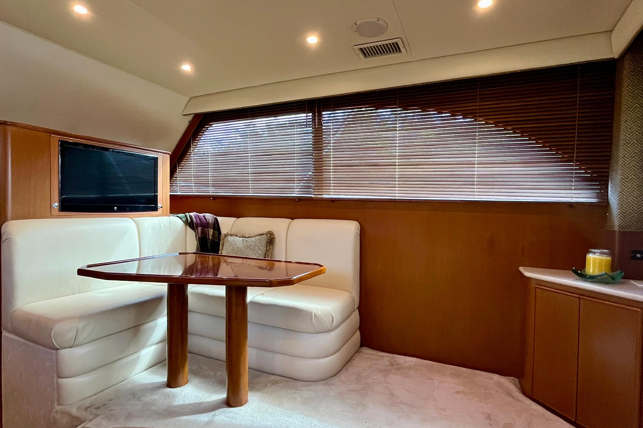 Interior of 1999 Post 42 Convertible yacht with cozy seating and wooden table.