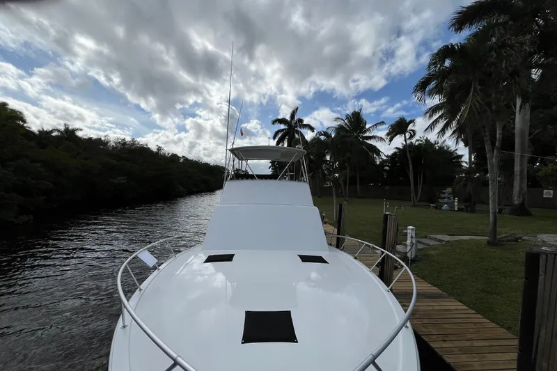 Next Yacht Photos Pics 1999 Post 42 Convertible yacht docked by palm trees under a cloudy sky.