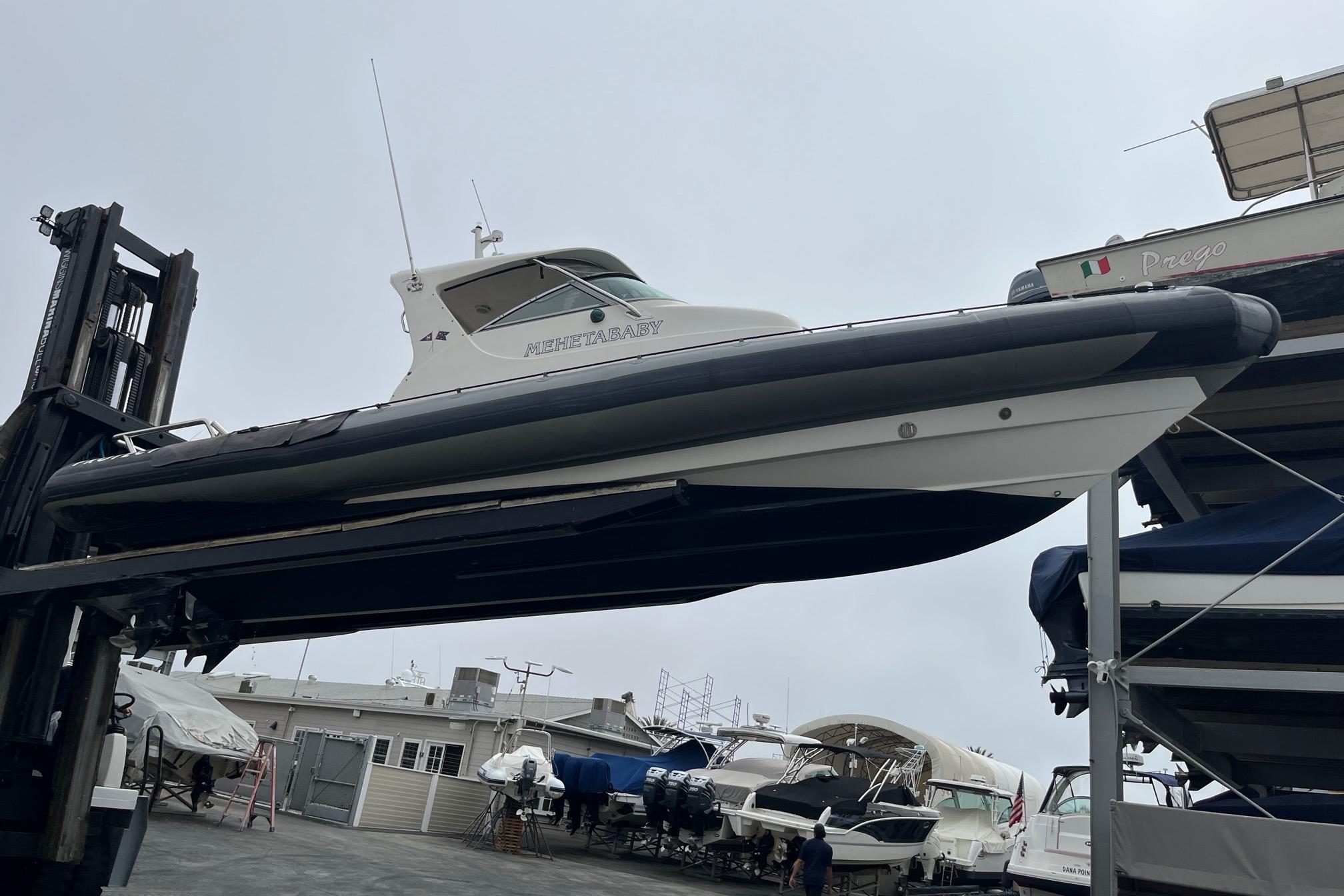 2001 Protector Targa 28 boat lifted in a marina storage area.