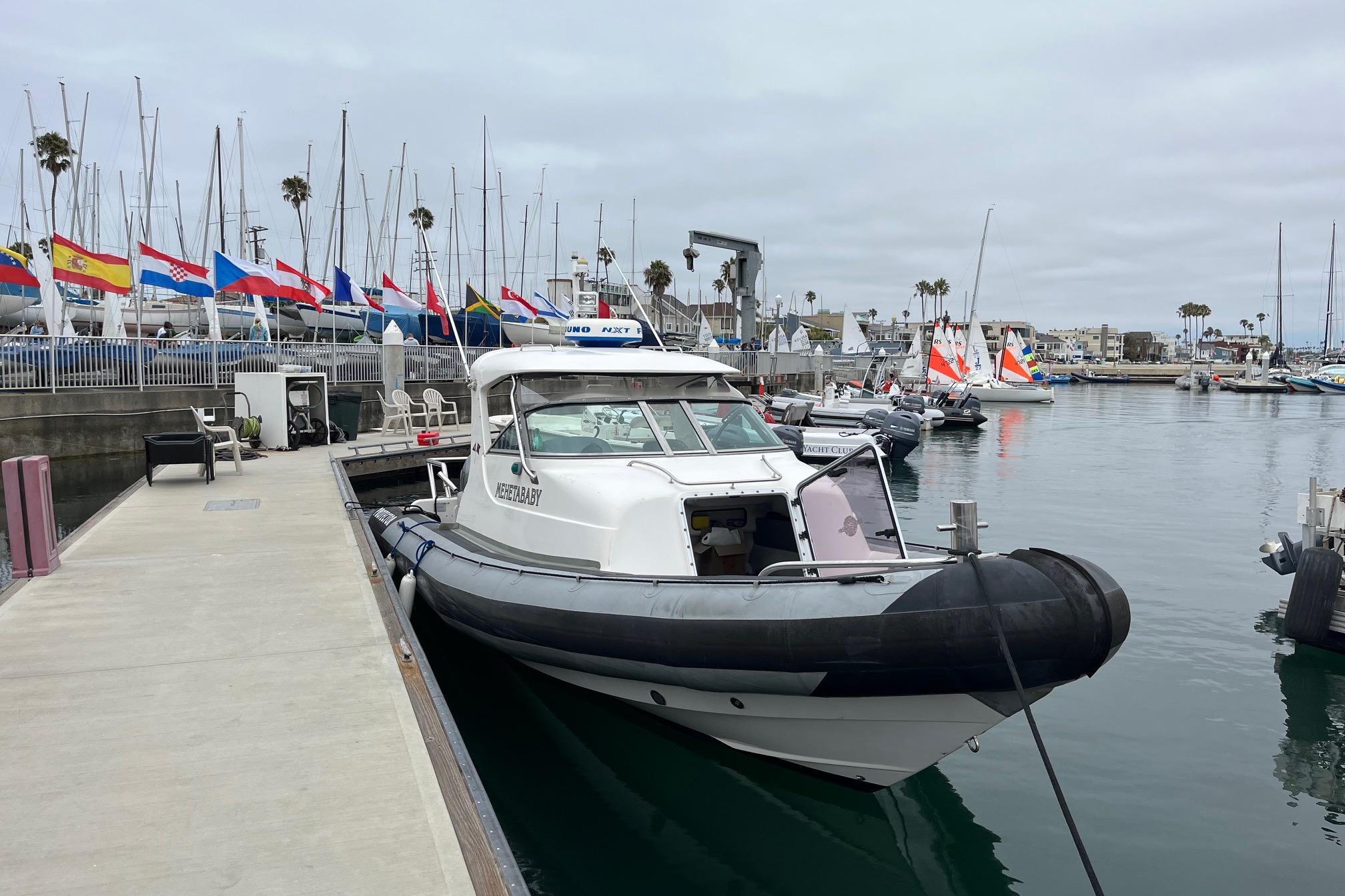 2001 Protector Targa 28 docked at marina with international flags in background.