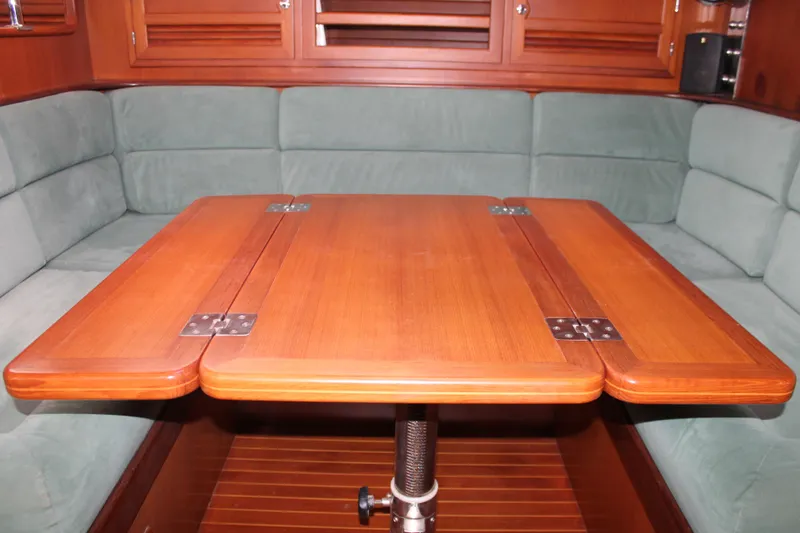 Callisto Yacht Photos Pics Wooden table in a 2009 Outbound 46 yacht interior with green cushioned seating.