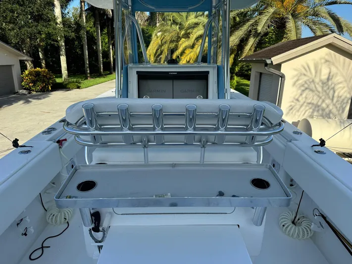  Yacht Photos Pics 2024 Contender 32 ST boat interior with rod holders and console, surrounded by lush greenery.