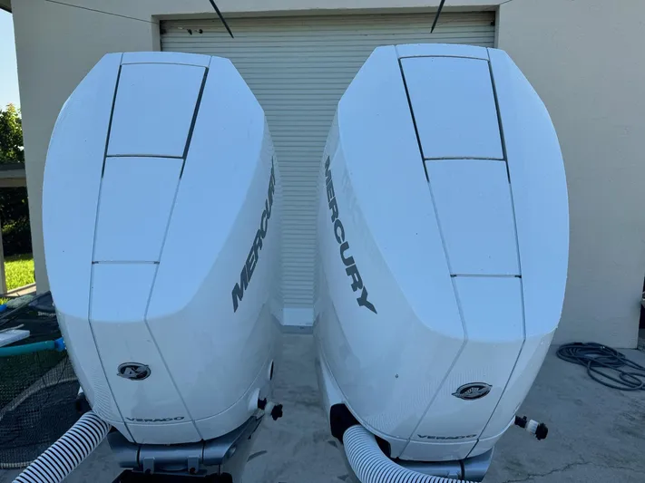  Yacht Photos Pics Twin Mercury outboard engines on a 2024 Contender 32 ST boat, parked near a garage.