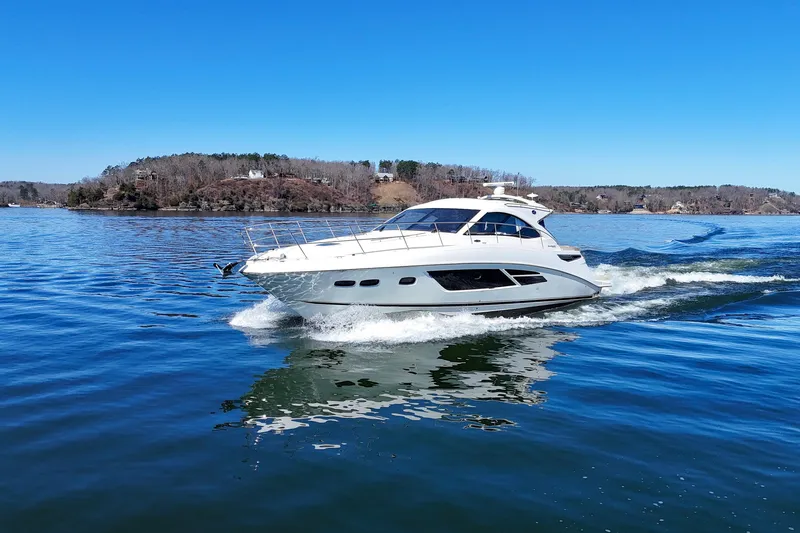  Yacht Photos Pics 2016 Sea Ray Sundancer 510 cruising on a serene lake under a clear blue sky.