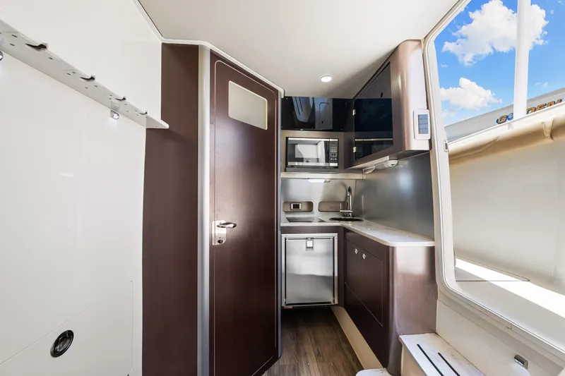  Yacht Photos Pics 2018 Scout 380 LXF boat interior kitchen with modern appliances and wood finish.
