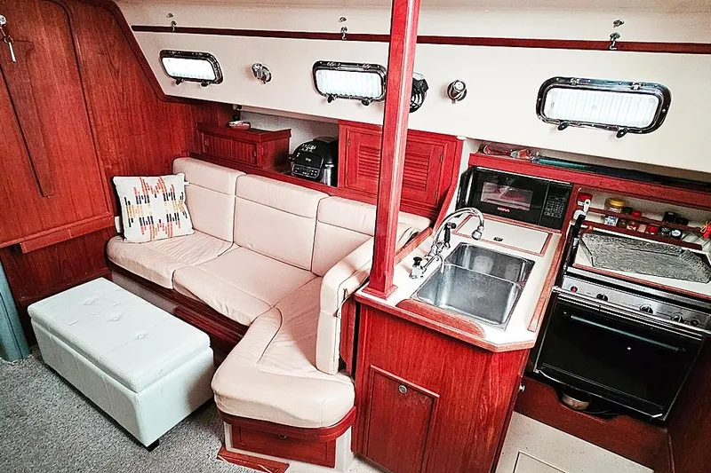  Yacht Photos Pics Interior of 2000 Island Packet 350 sailboat with cozy seating and compact kitchen area.