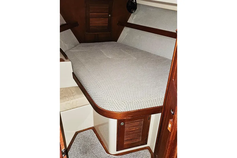  Yacht Photos Pics Cozy cabin interior of 2000 Island Packet 350 sailboat with wooden accents and cushioned berth.