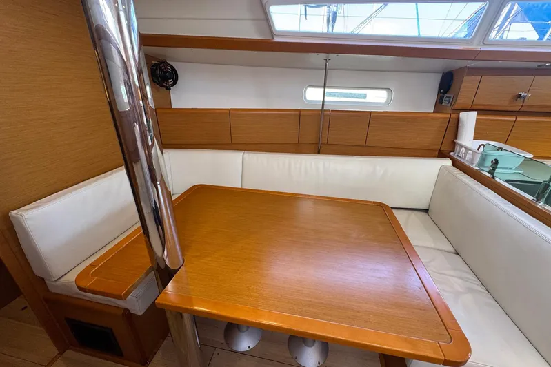 Sea Ranch II Yacht Photos Pics 2018 Jeanneau Sun Odyssey 389 interior with wooden table and white seating.