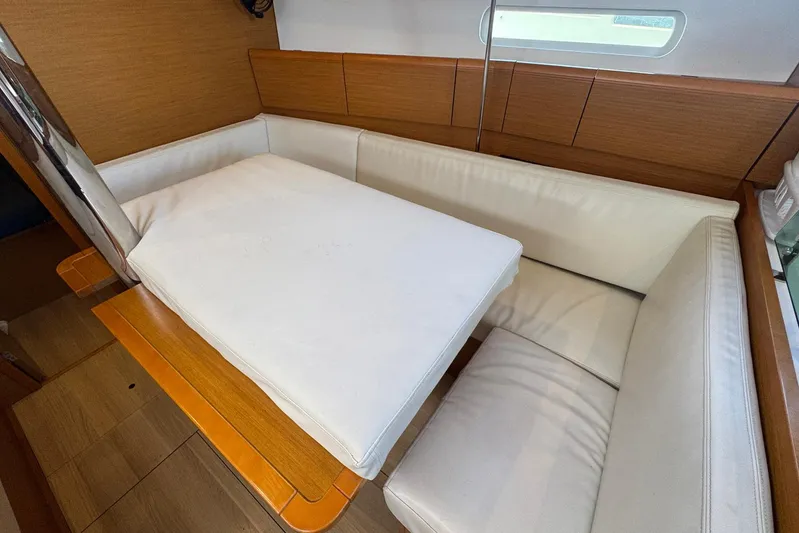 Sea Ranch II Yacht Photos Pics Interior of 2018 Jeanneau Sun Odyssey 389 with white cushioned seating and wooden accents.