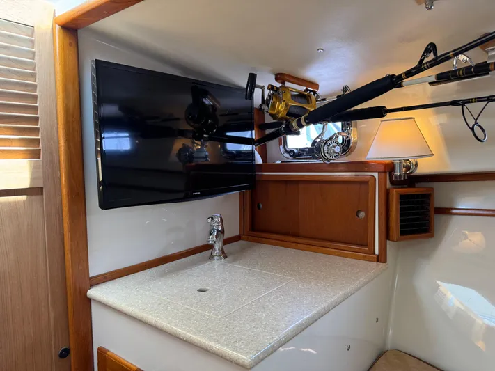 Wrecking Crew Yacht Photos Pics Interior of a 2006 Fortier 26 boat with TV, fishing rods, and countertop.