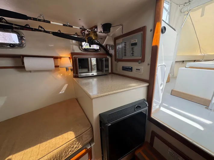 Wrecking Crew Yacht Photos Pics Interior of 2006 Fortier 26 boat with kitchenette, fishing rods, and control panel.