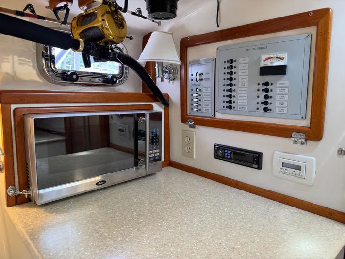 Wrecking Crew Yacht Photos Pics Interior of 2006 Fortier 26 boat with microwave, control panel, and fishing rod.