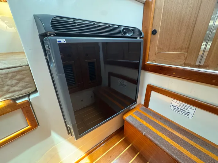 Wrecking Crew Yacht Photos Pics Interior of a 2006 Fortier 26 boat featuring a compact refrigerator and wooden accents.