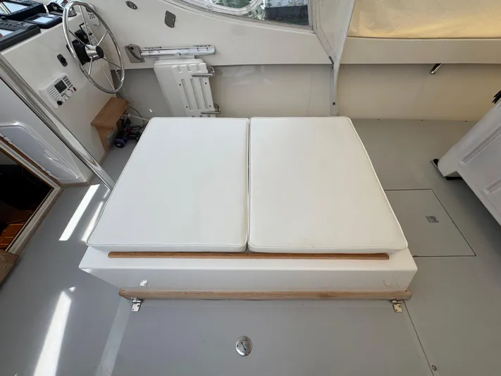 Wrecking Crew Yacht Photos Pics Interior of a 2006 Fortier 26 boat with white cushioned seating and steering wheel.