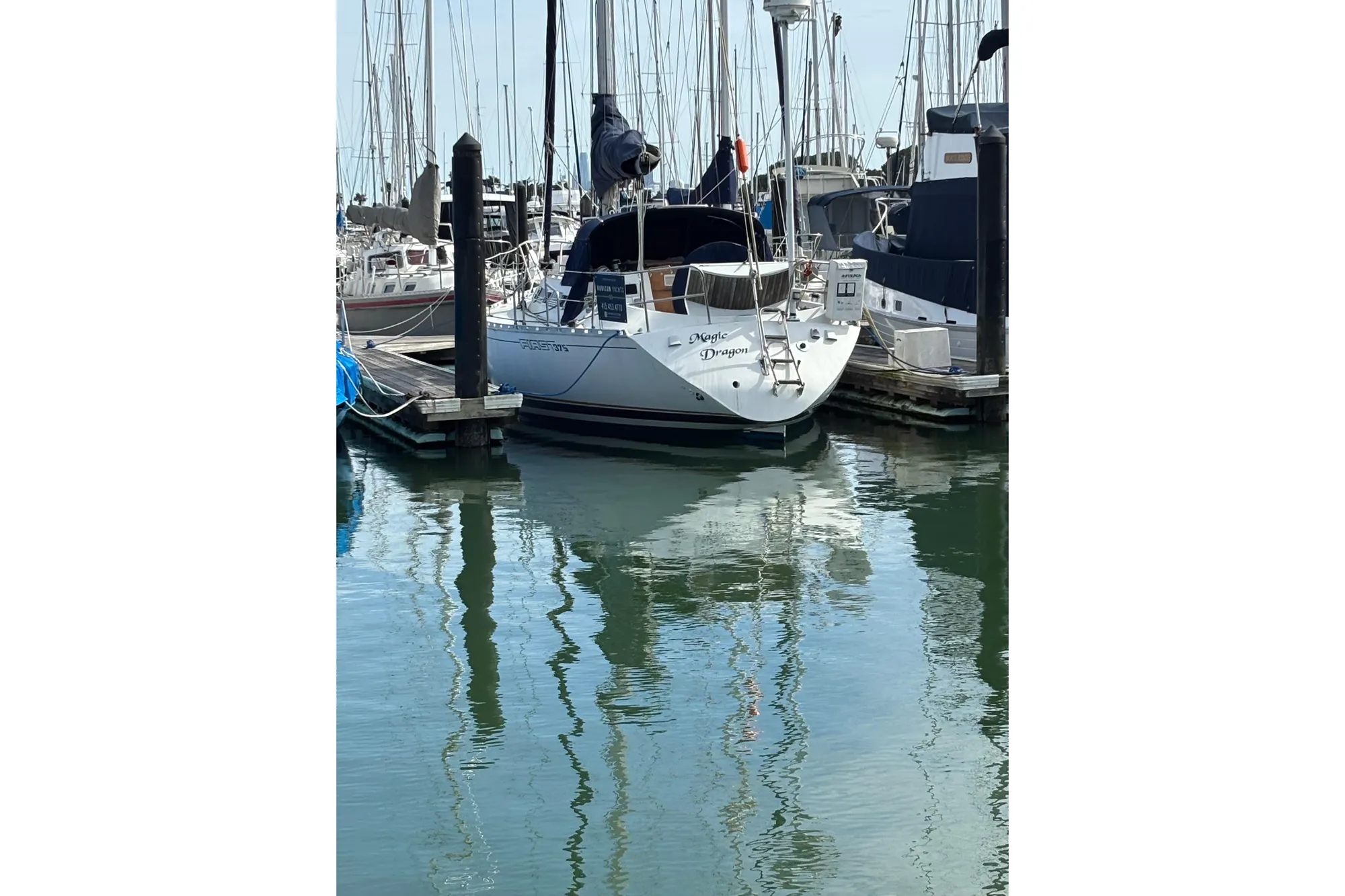 1986 Beneteau First 375 sailboat docked in a marina, reflecting on calm water.
