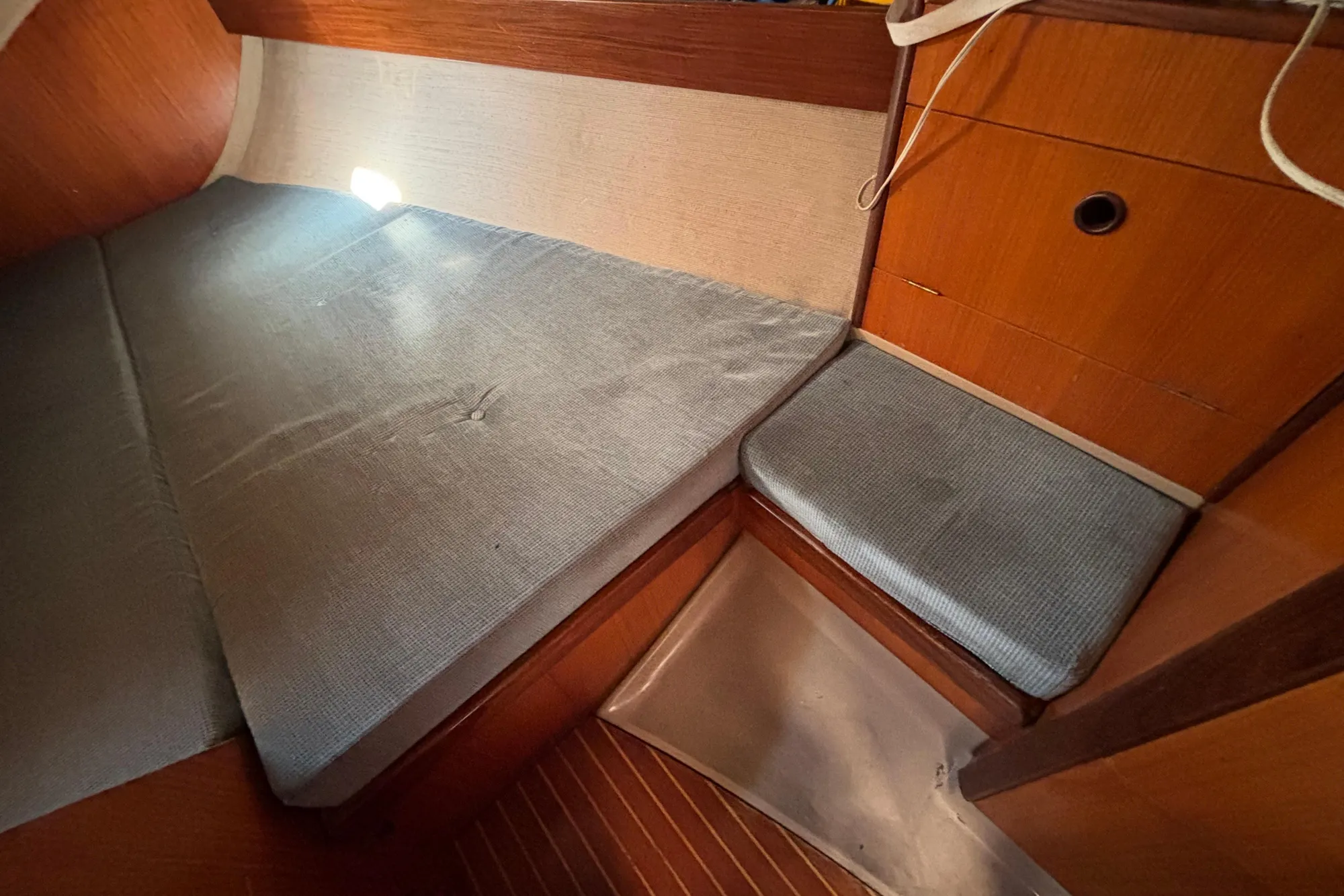 Cozy cabin interior of 1986 Beneteau First 375 sailboat with blue cushions.