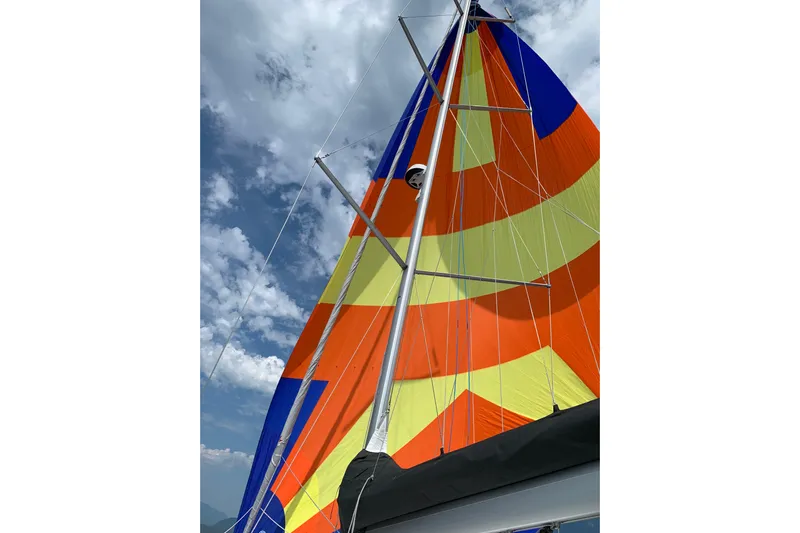 Lost Traveler Yacht Photos Pics Colorful sail of 2020 Jeanneau Sun Odyssey 440 against a cloudy sky.