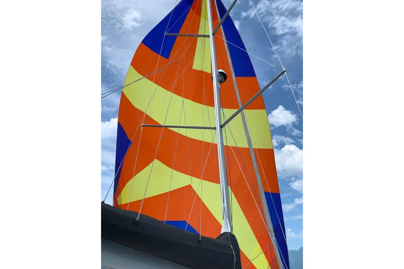 Lost Traveler Yacht Photos Pics Colorful sail of a 2020 Jeanneau Sun Odyssey 440 against a cloudy sky.