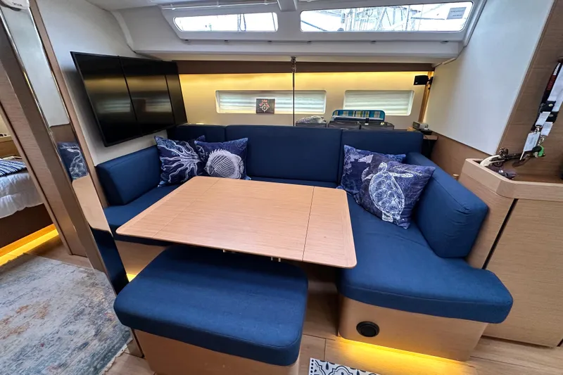Lost Traveler Yacht Photos Pics Luxurious interior of 2020 Jeanneau Sun Odyssey 440 yacht with blue seating and wooden table.