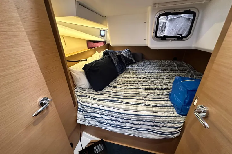 Lost Traveler Yacht Photos Pics Cozy cabin interior of 2020 Jeanneau Sun Odyssey 440 sailboat with striped bedding.
