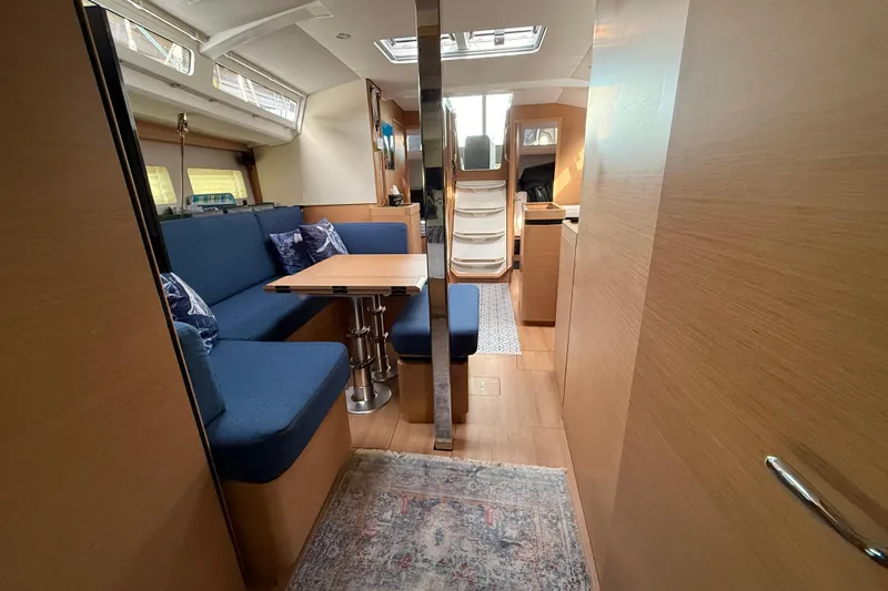 Lost Traveler Yacht Photos Pics Interior of 2020 Jeanneau Sun Odyssey 440 yacht with blue seating and wooden finishes.