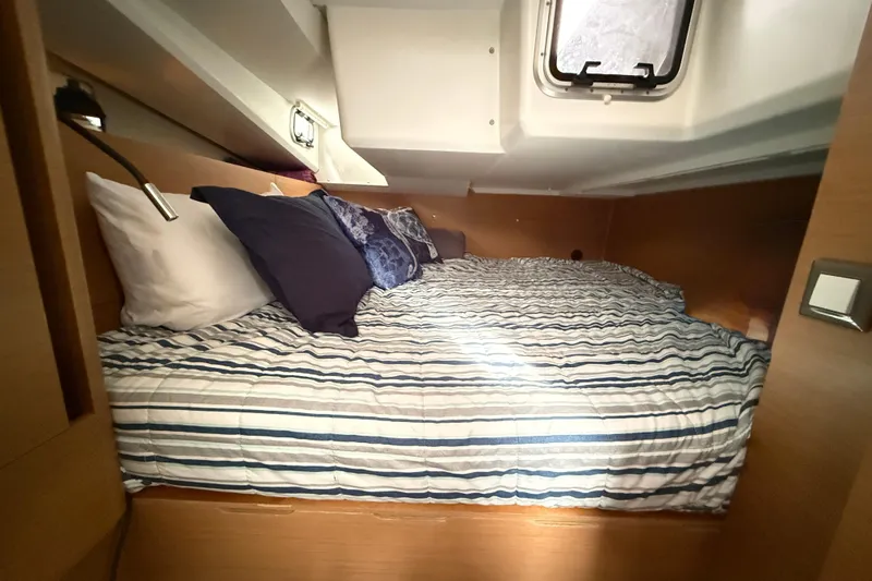 Lost Traveler Yacht Photos Pics Cozy cabin interior of 2020 Jeanneau Sun Odyssey 440 sailboat with striped bedding.