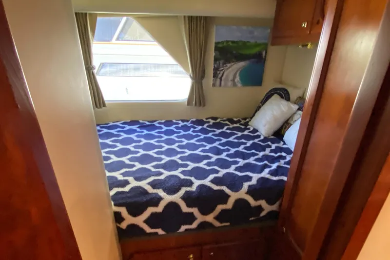 Dianne Yacht Photos Pics Cozy cabin interior of 2003 Bluewater Yachts 6000, featuring a patterned bedspread and window view.