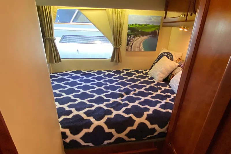 Dianne Yacht Photos Pics Cozy bedroom in 2003 Bluewater Yachts 6000, featuring patterned bedding and scenic artwork.
