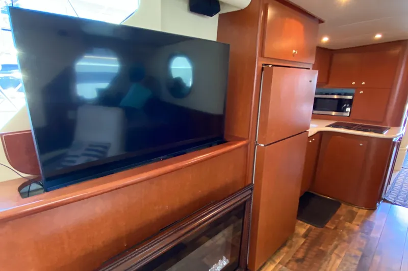 Dianne Yacht Photos Pics Interior of 2003 Bluewater Yachts 6000, featuring TV, kitchen, and wooden cabinetry.