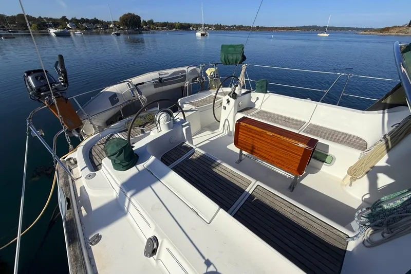 Bellabeaupied Yacht Photos Pics 2004 Beneteau 473 sailboat deck with steering wheel, wooden seating, and scenic water view.