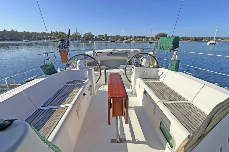 Bellabeaupied Yacht Photos Pics 2004 Beneteau 473 sailboat cockpit with dual steering wheels, docked on a calm lake.