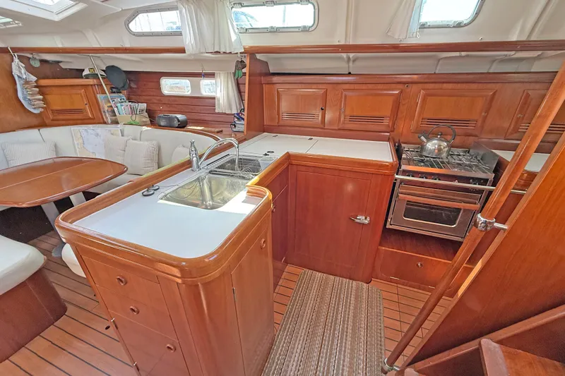Bellabeaupied Yacht Photos Pics Interior of 2004 Beneteau 473 yacht with wooden cabinetry and compact kitchen area.