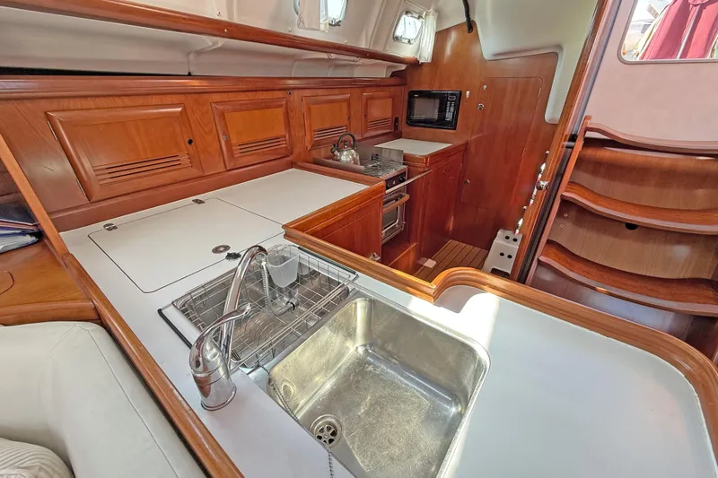 Bellabeaupied Yacht Photos Pics Luxurious 2004 Beneteau 473 yacht kitchen with wood cabinetry and modern appliances.