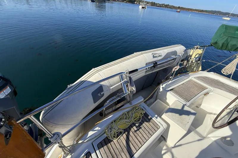 Bellabeaupied Yacht Photos Pics 2004 Beneteau 473 sailboat deck with dinghy, moored on calm water.