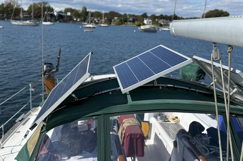 Bellabeaupied Yacht Photos Pics 2004 Beneteau 473 sailboat with solar panels on deck, anchored in a scenic harbor.