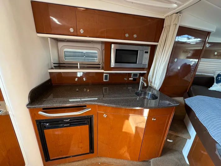  Yacht Photos Pics 2014 Sea Ray 330 Sundancer interior kitchen with wood cabinets, microwave, and sink.