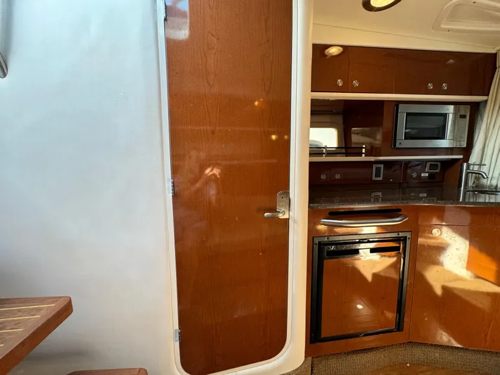  Yacht Photos Pics Interior of 2014 Sea Ray 330 Sundancer with kitchenette, featuring wood cabinetry and modern appliances.