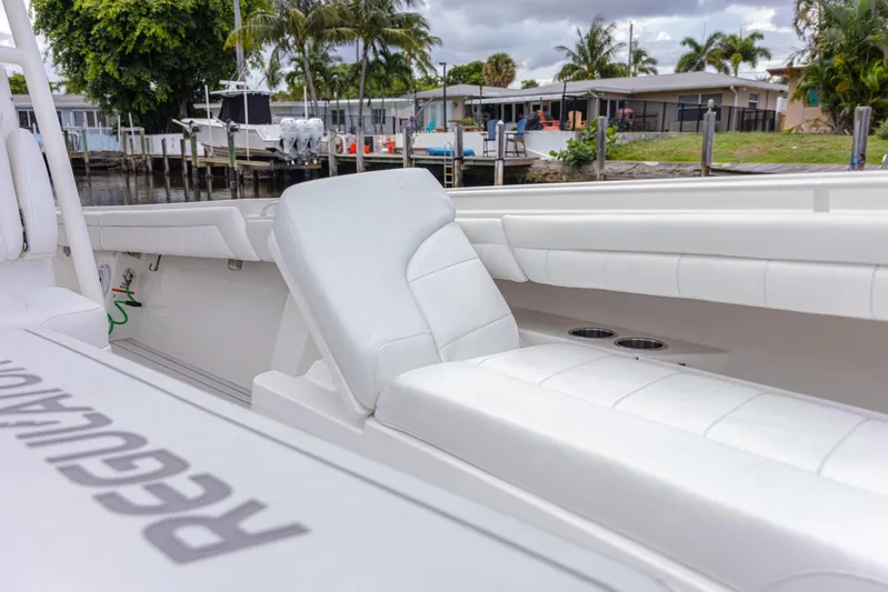  Yacht Photos Pics 2019 Regulator 34 boat with white seating, docked near waterfront homes.