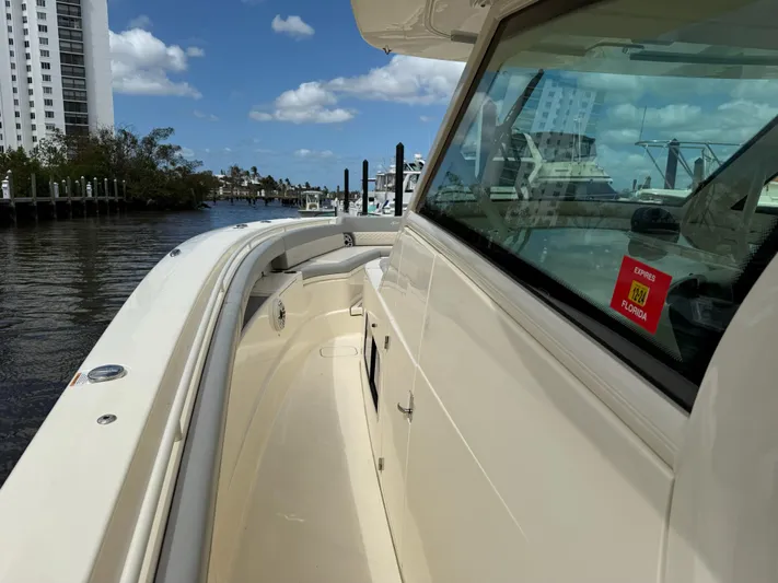  Yacht Photos Pics 2022 Scout 425 LXF boat docked by waterfront buildings under a clear blue sky.